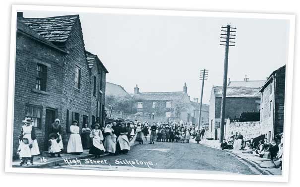 This view looking up the High Street in Silkstone shows a number of buildings which have changed relatively little over the years, apart from, of course, the groups of people who are gathered in the street posing for the photographers.